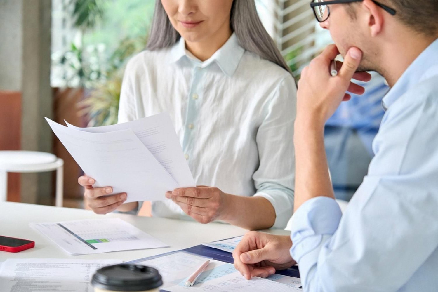 Two analysts reading a supplier due diligence report at a UAE office desk